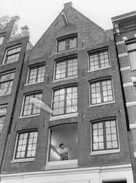    The facade of Keizersgracht 10. Gusta Drenthe, of LOVER, is standing by the open window. 1981